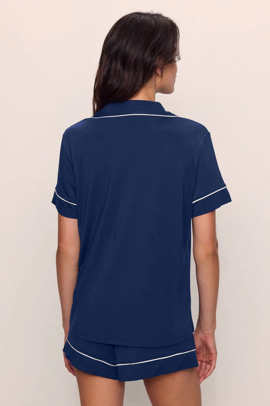 Person wearing a navy blue pajama set with white trim on a plain background from Eberjey