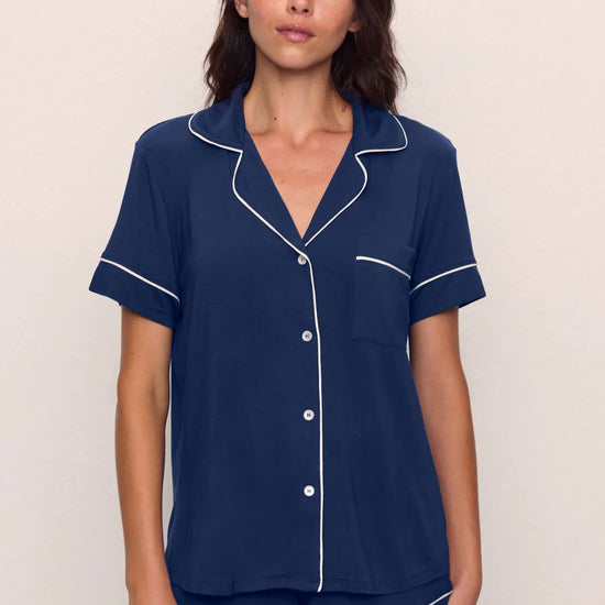 Woman wearing navy blue pajamas with white piping from Eberjey