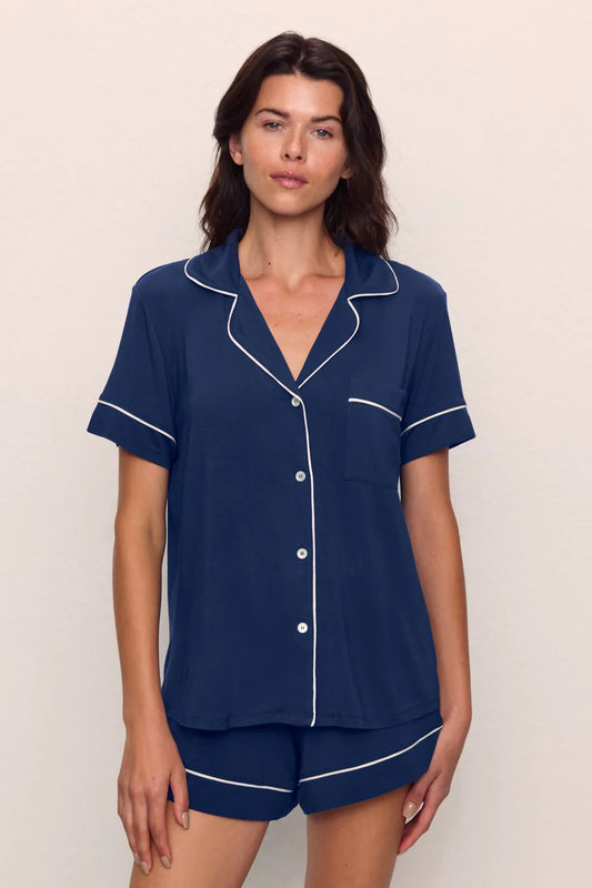 Woman wearing navy blue pajamas with white piping from Eberjey