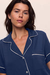 Woman wearing a navy blue pajama top with white piping from Eberjey