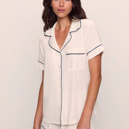 Woman wearing a white pajama set with navy piping from Eberjey 