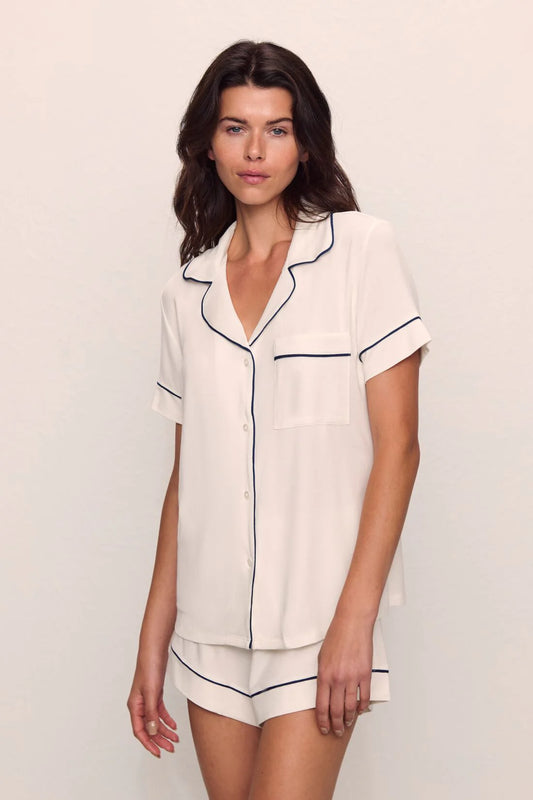 Woman wearing a white pajama set with navy piping from Eberjey 