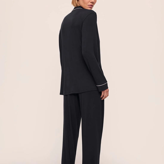 Woman wearing a black suit with white trim on a beige background