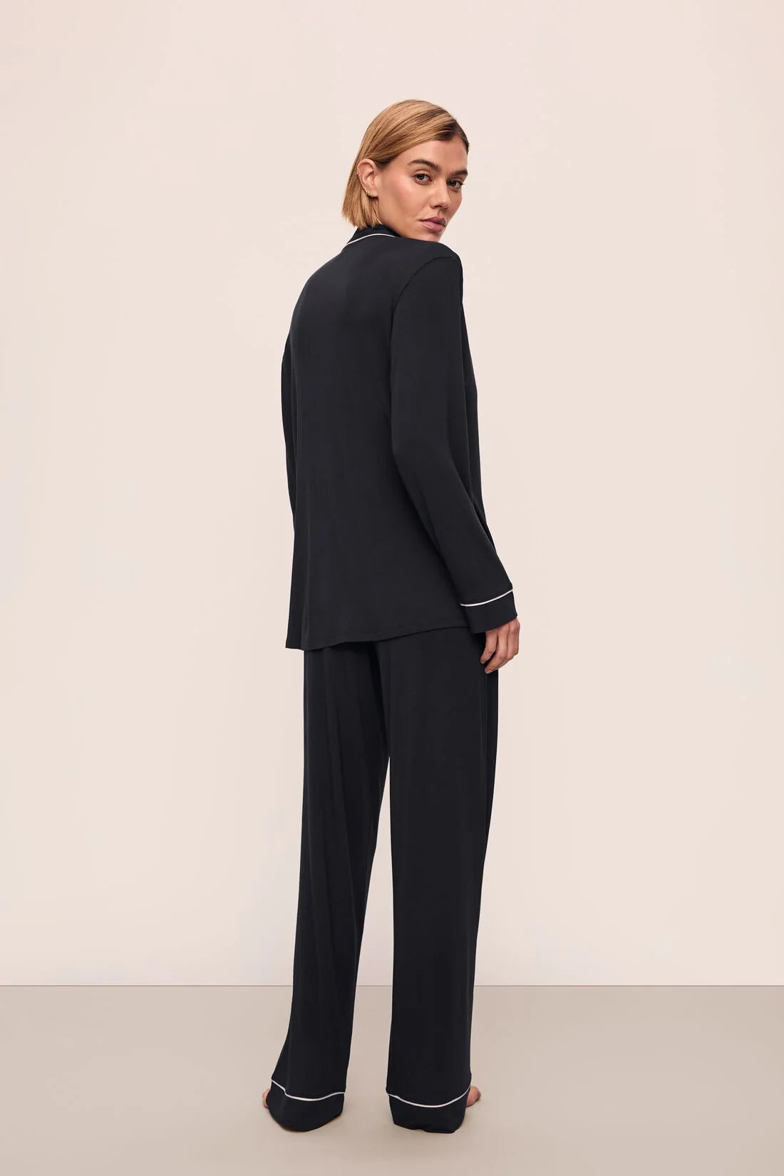 Woman wearing a black suit with white trim on a beige background