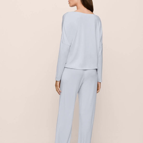 Woman wearing light blue pajamas against a beige background