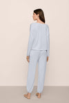 Woman wearing light blue pajamas against a beige background