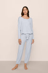 Woman wearing light blue pajama set on a beige background