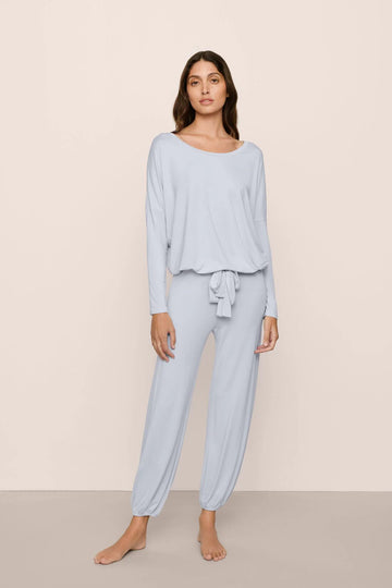 Woman wearing light blue pajama set on a beige background