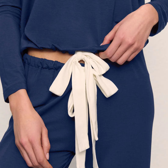 Person wearing blue pants with white drawstrings on a neutral background