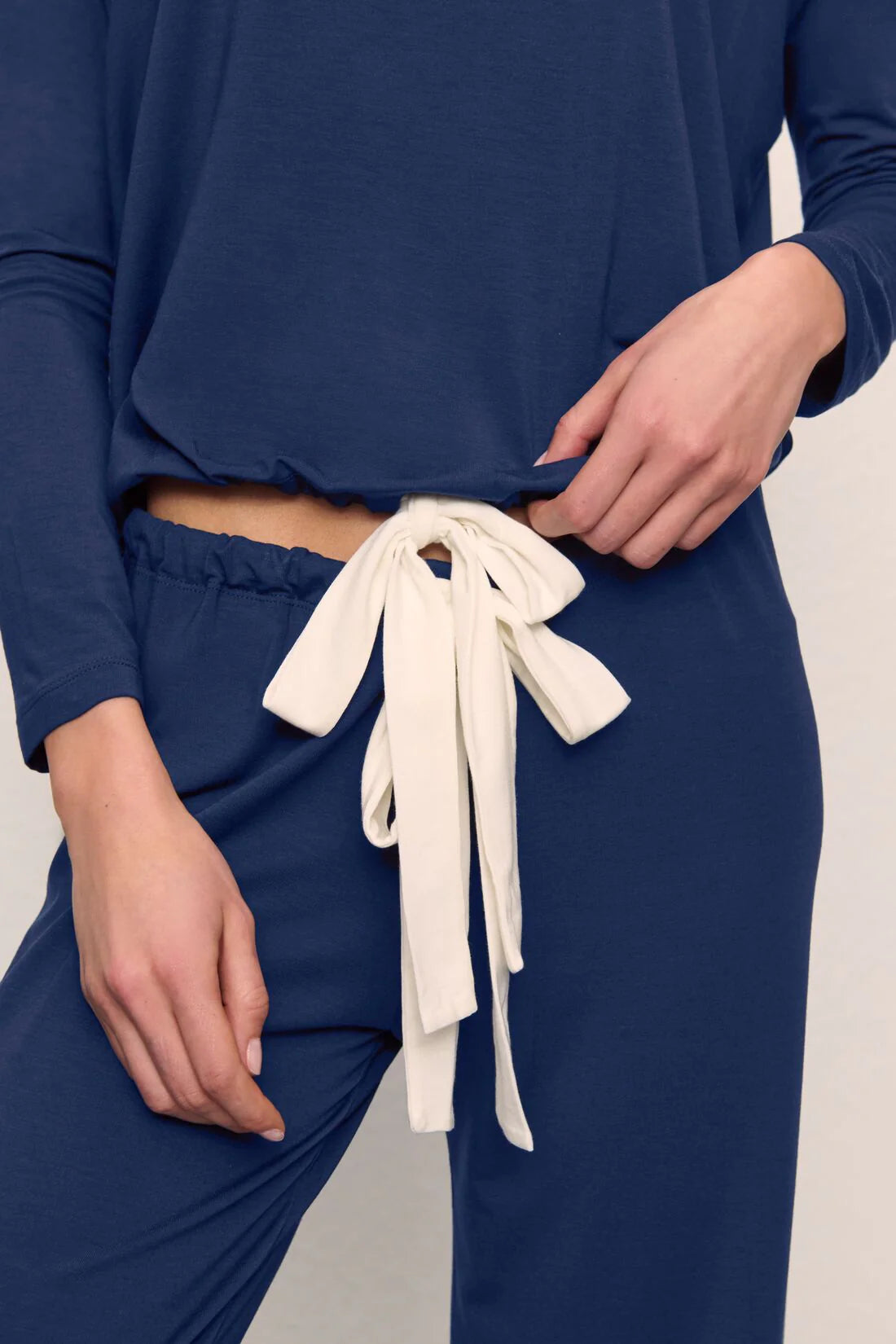 Person wearing blue pants with white drawstrings on a neutral background