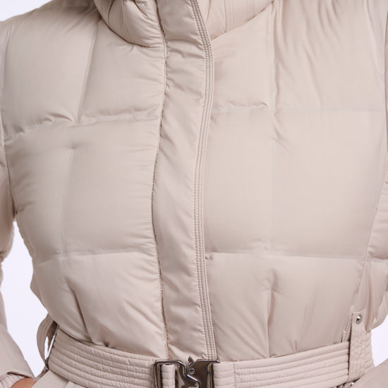 Close-up of a beige hooded puffer jacket with a matching belt and silver buckle, shown on a model.