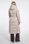 A woman viewed from the back wearing a long, light beige hooded puffer coat with a quilted grid pattern and a matching waist belt, paired with dark wide-leg trousers and black shoes, against a plain light gray studio background.