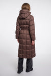 A model viewed from the back wearing a long brown puffer coat with a hood and waist belt, paired with black pants, against a light gray studio background.