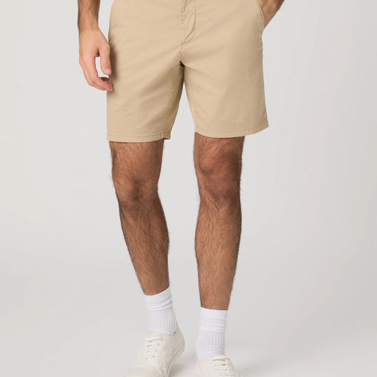 Person wearing beige shorts on a plain background from Paige