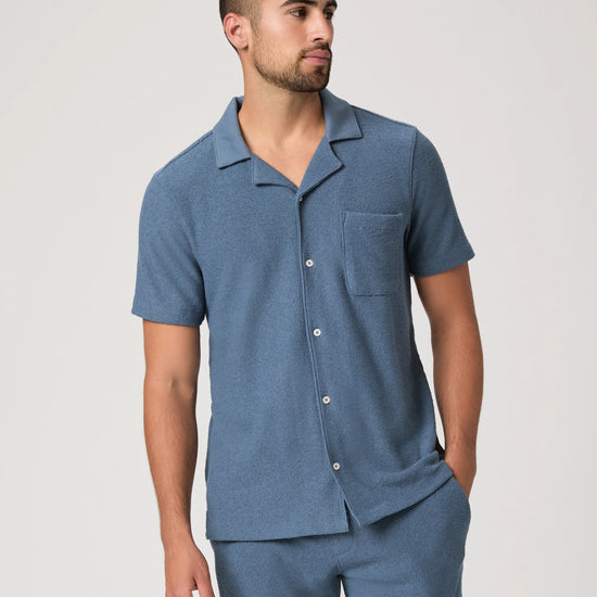 Man wearing a blue paige shirt on a white background