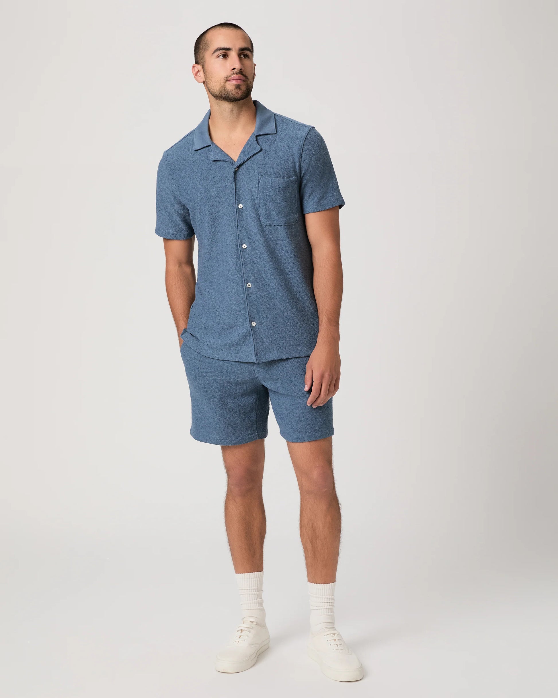 Man wearing a blue paige shirt abd matching shorts on a white background