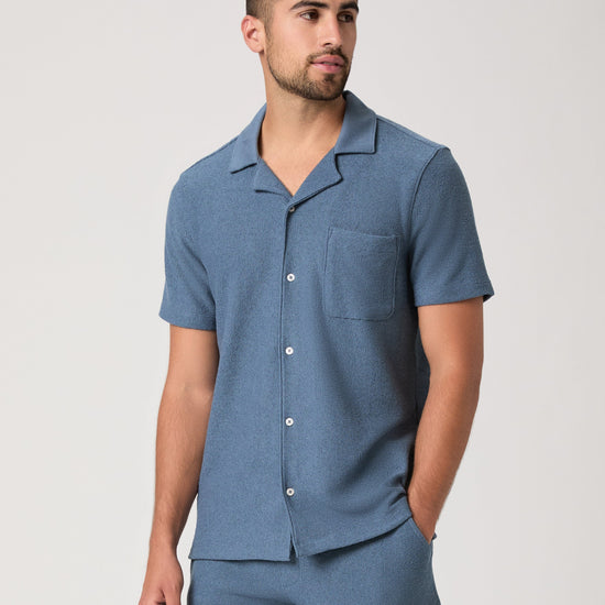 Man wearing a blue paige shirt on a white background close up