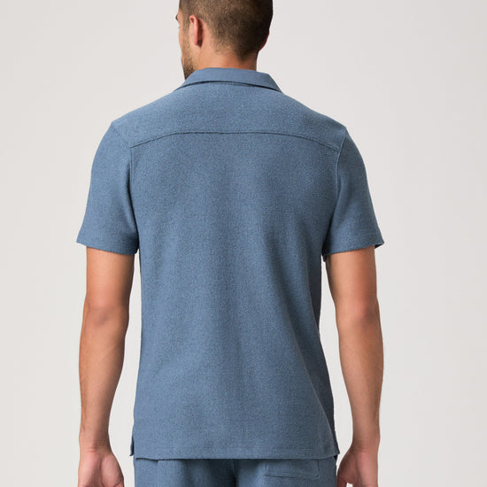 Man wearing a blue paige shirt on a white background rear view