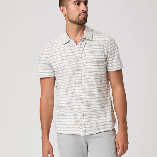 Man wearing a striped shirt and light gray pants on a white background
