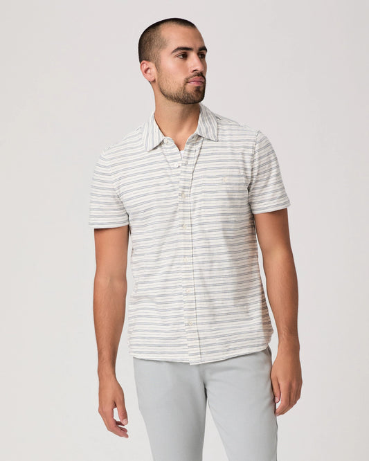Man wearing a striped shirt and light gray pants on a white background