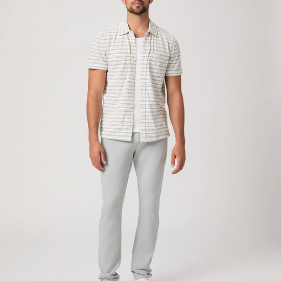 Man wearing a striped shirt and light gray pants on a white background