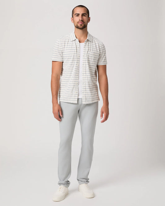Man wearing a striped shirt and light gray pants on a white background