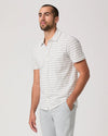 Man wearing a white striped shirt and light gray pants on a plain background
