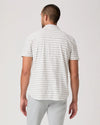 Man wearing a striped polo shirt and light gray pants on a white background
