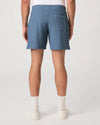 Person wearing blue Paige shorts and white shoes on a plain background rear view