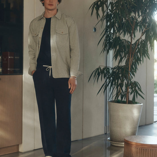 Man wearing Navy blue pants with a white drawstring by Paige with stripe jacket