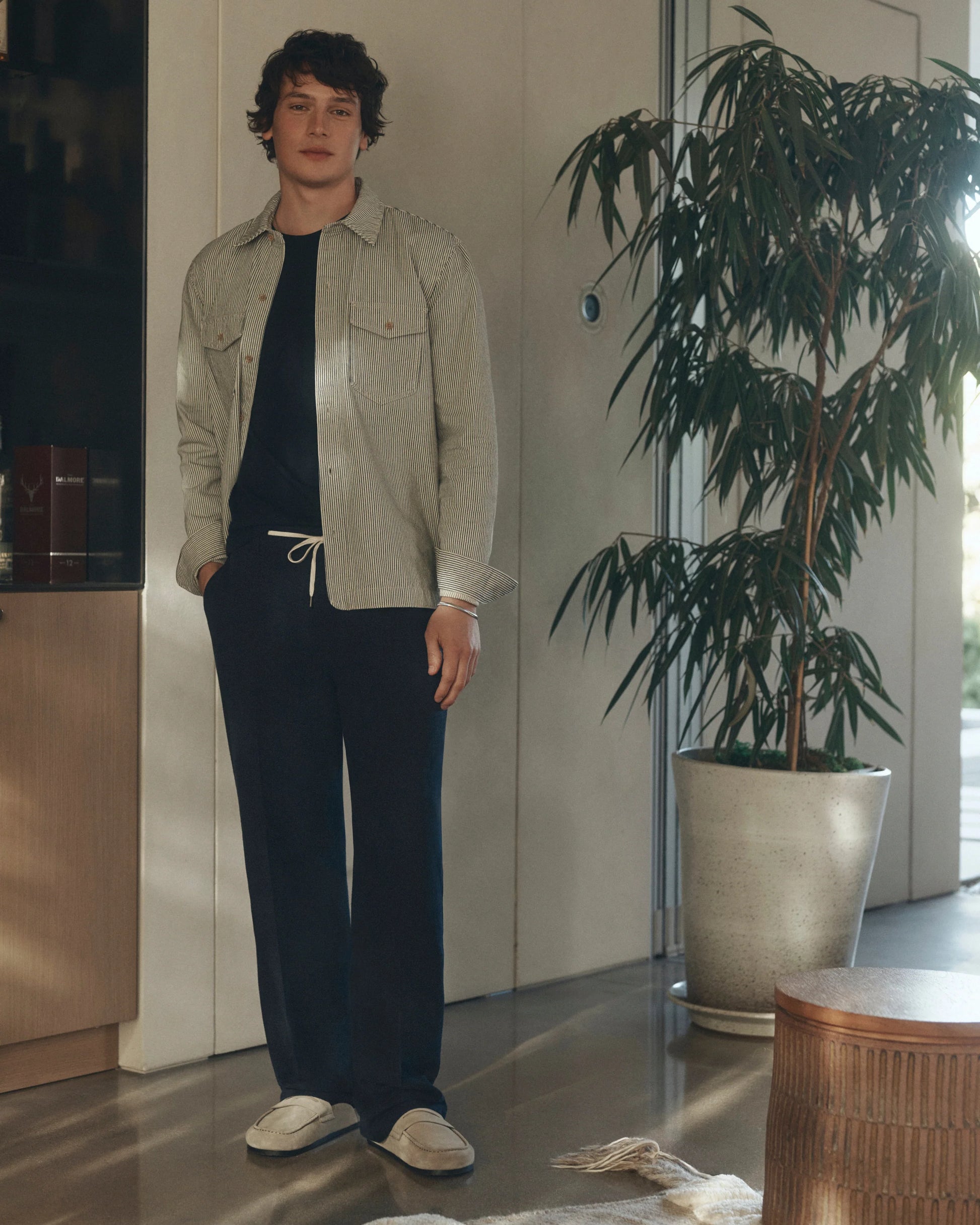 Man wearing Navy blue pants with a white drawstring by Paige with stripe jacket
