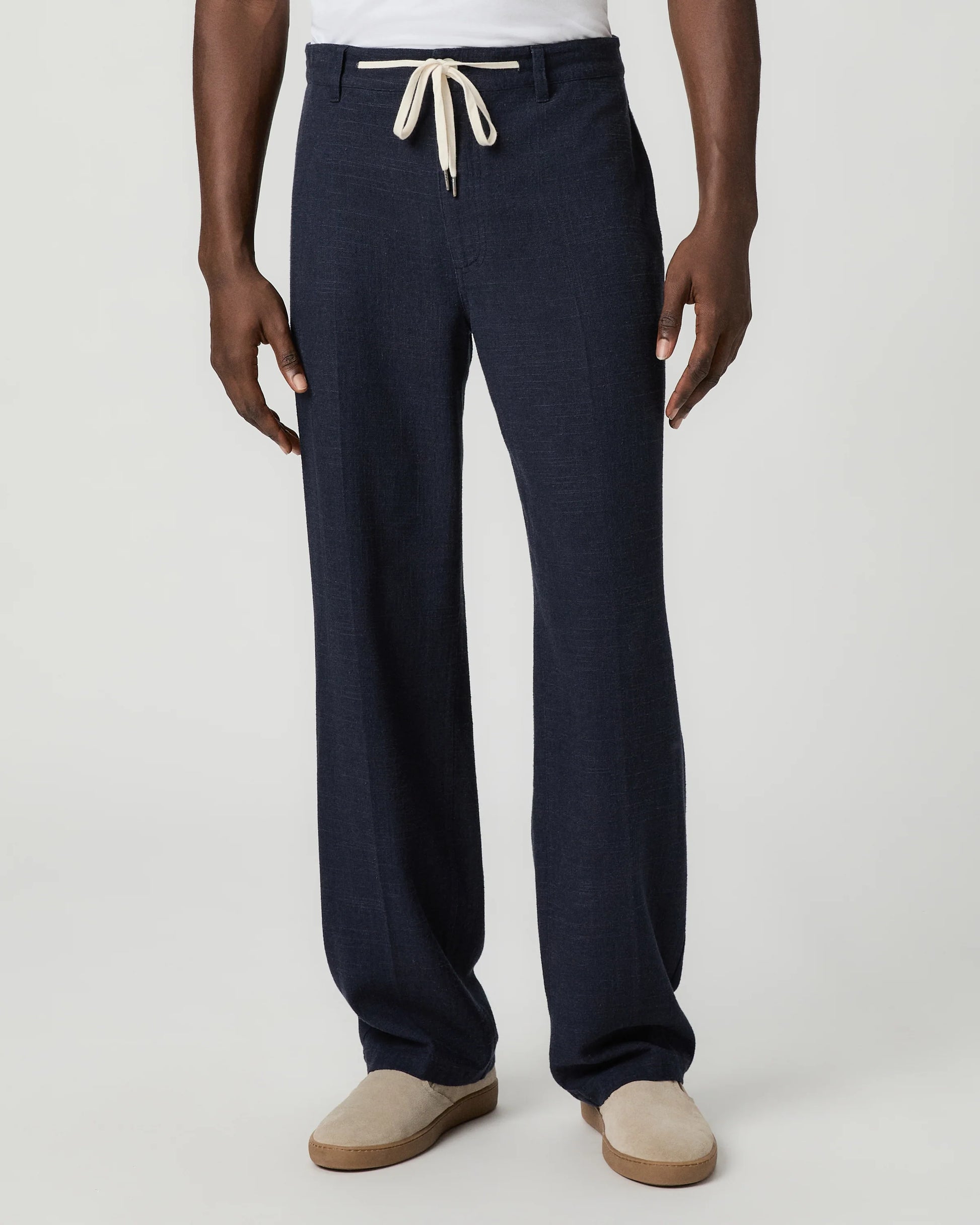 Navy blue pants with a white drawstring by Paige worn by a man on a light gray background