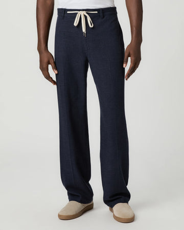 Navy blue pants with a white drawstring by Paige worn by a man on a light gray background
