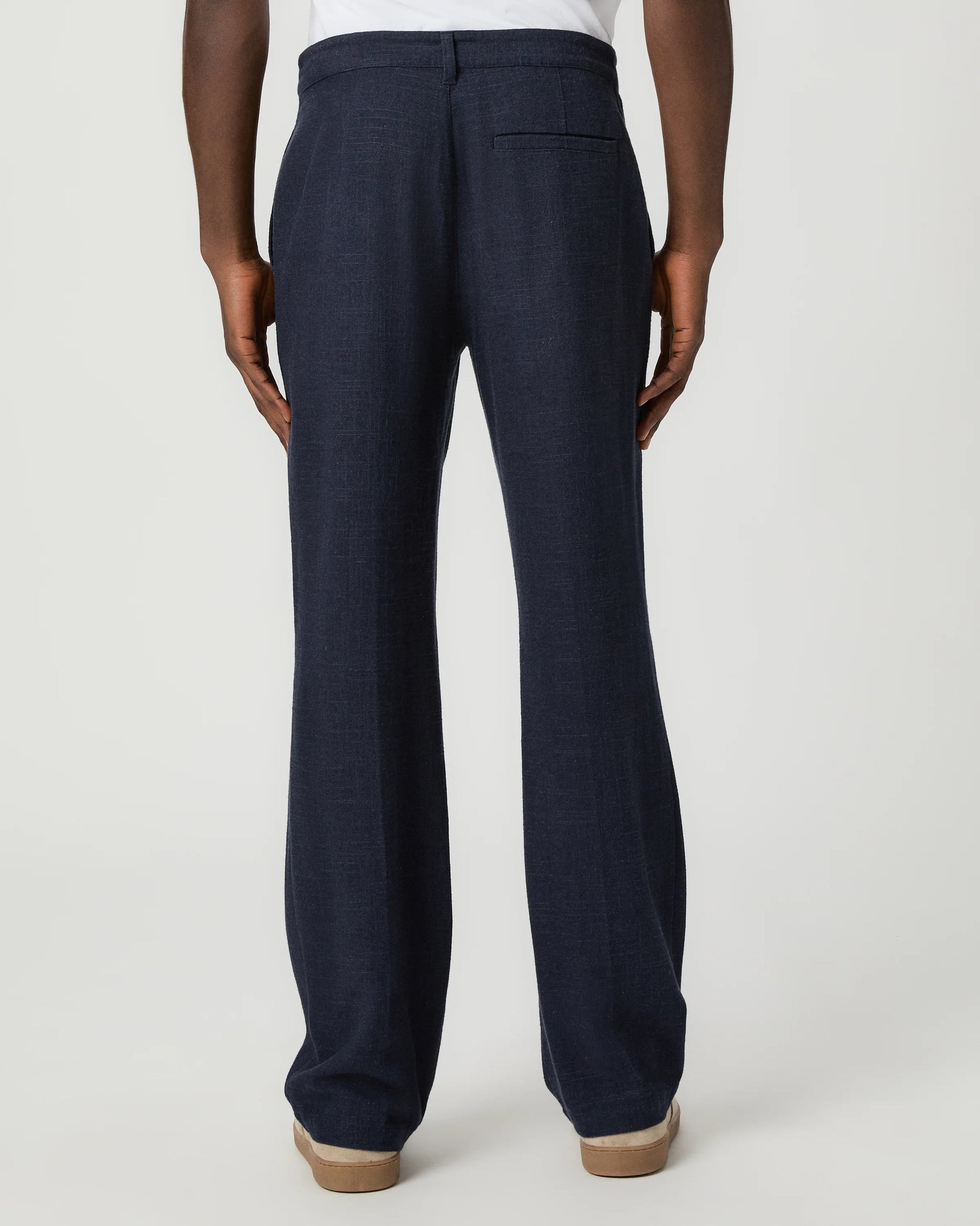 Navy blue pants with a white drawstring by Paige worn by a man on a light gray background rear view