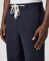 Navy blue pants with a white drawstring by Paige worn by a man on a light gray background close up