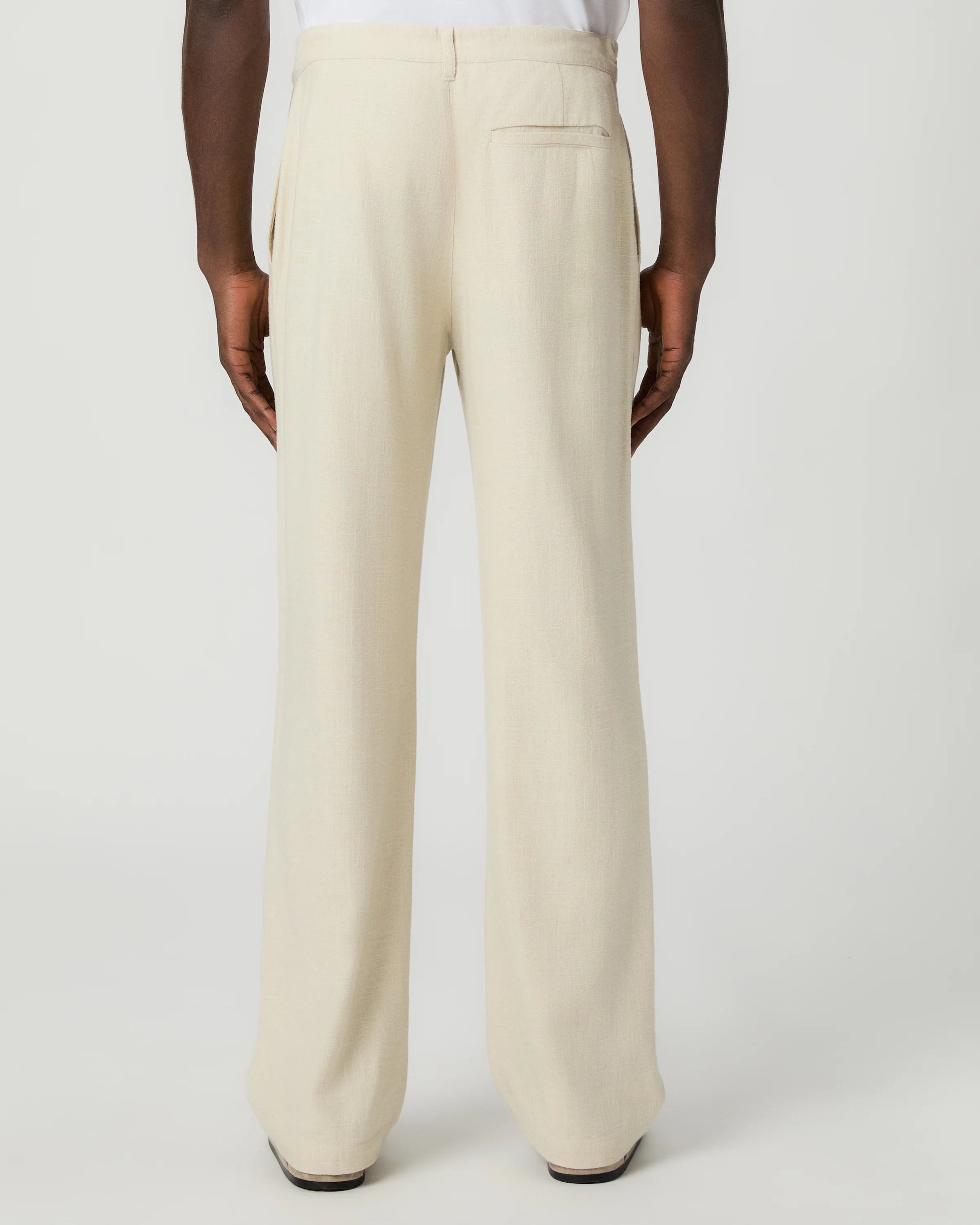 Beige paige pants worn by a man on a white background rear view