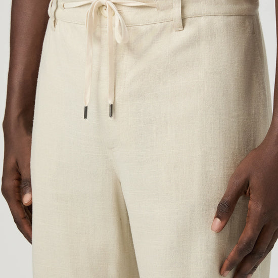Beige paige pants worn by a man on a white background close up