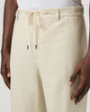 Beige paige pants worn by a man on a white background close up