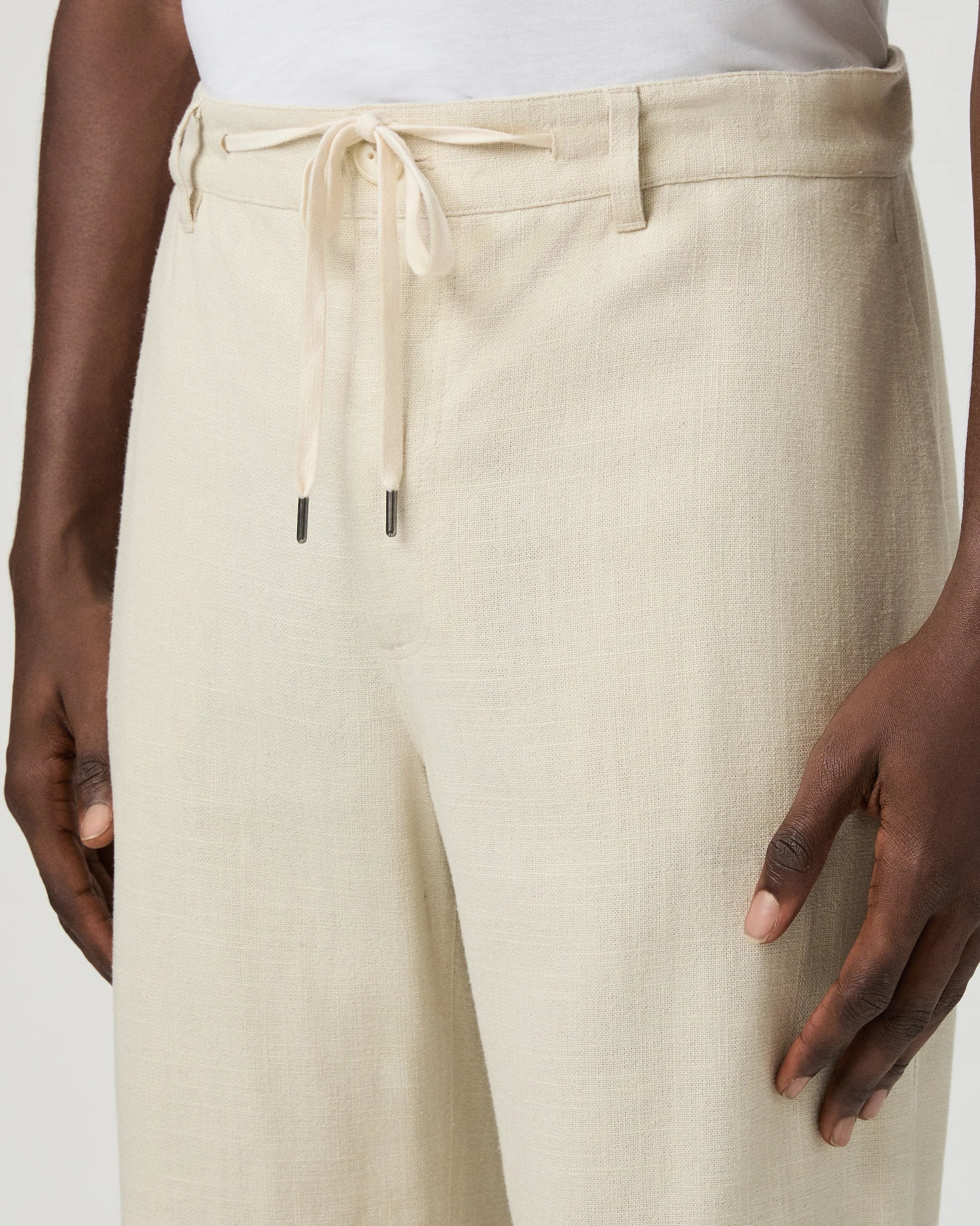 Beige paige pants worn by a man on a white background close up