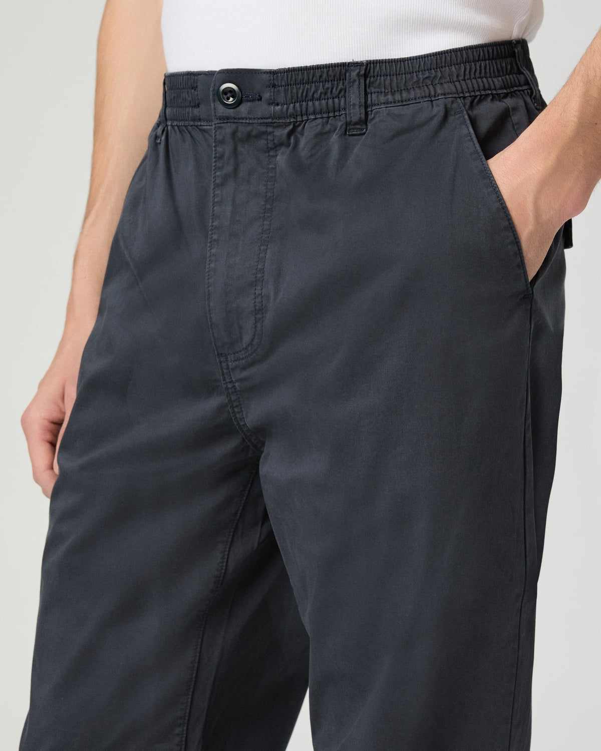 Navy pants worn by a person on a light gray background