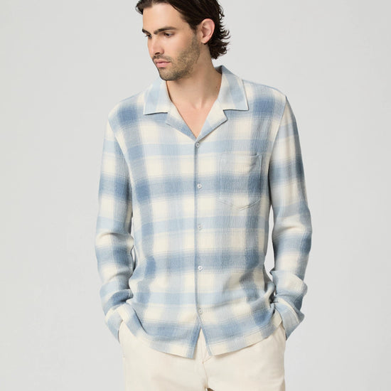 Man wearing a blue and white plaid shirt against a plain background from paige