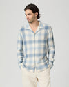 Man wearing a blue and white plaid shirt against a plain background from paige