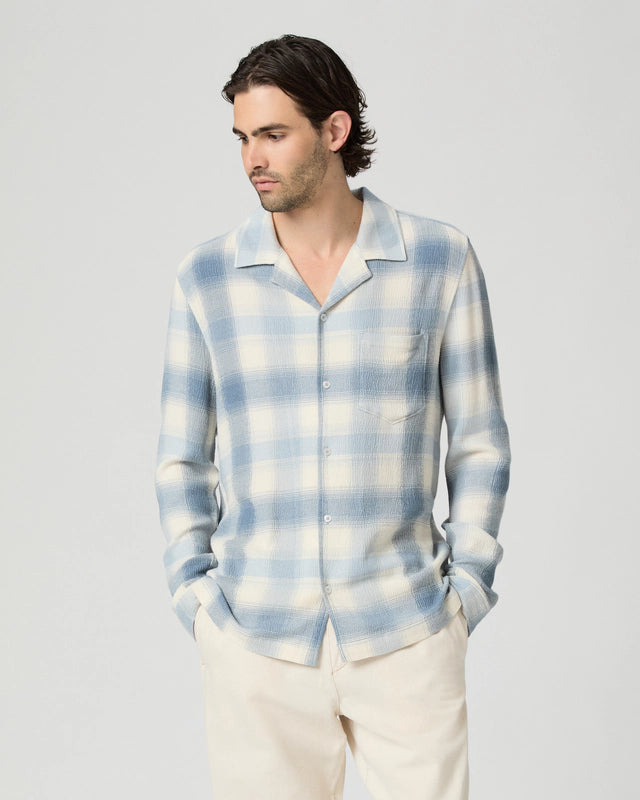 Man wearing a blue and white plaid shirt against a plain background from paige