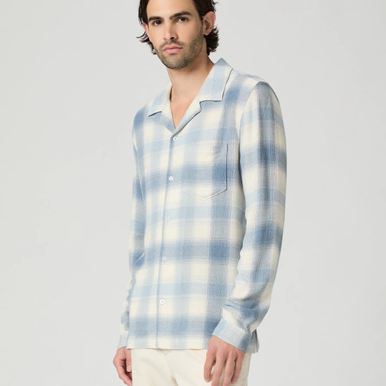 Man wearing a blue and white plaid shirt against a plain background from Paige