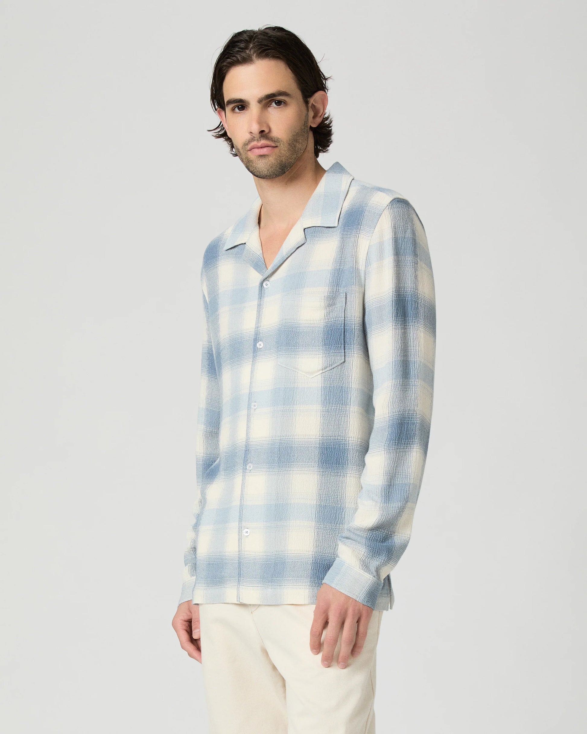 Man wearing a blue and white plaid shirt against a plain background from Paige