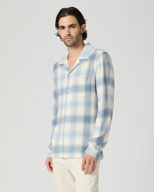 Man wearing a blue and white plaid shirt against a plain background from Paige