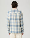 Person wearing a blue and white checkered shirt on a gray background from Paige