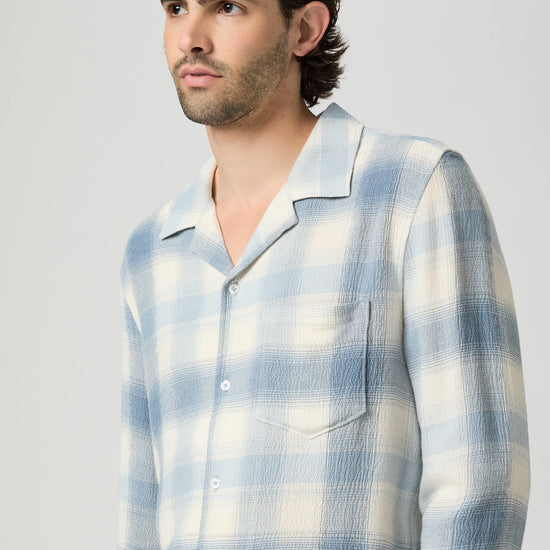 Man wearing a blue and white checkered shirt against a plain background from paige