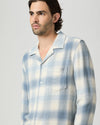 Man wearing a blue and white checkered shirt against a plain background from paige