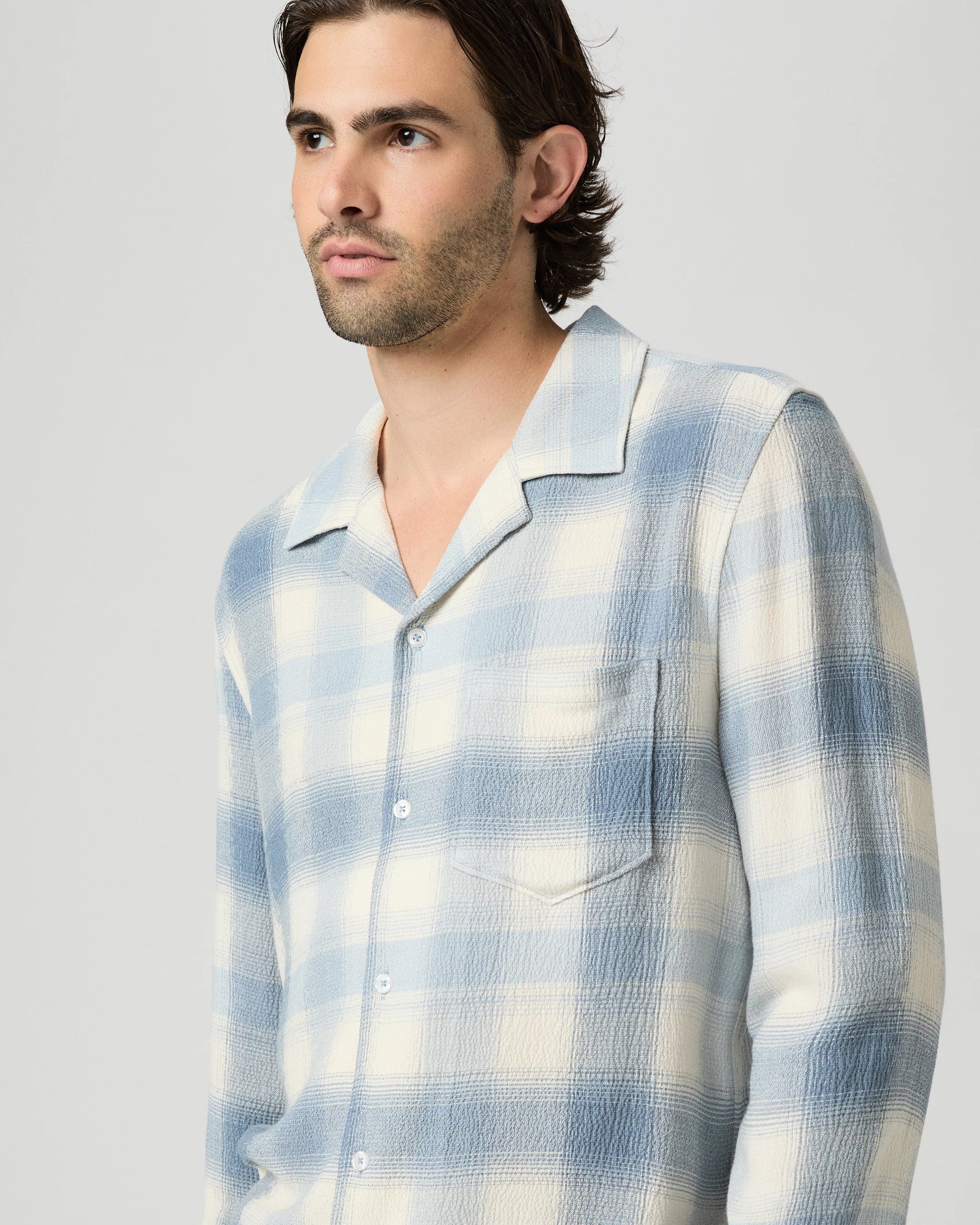 Man wearing a blue and white checkered shirt against a plain background from paige